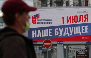 En San Petersburgo, una persona con tapabocas pasa frente a un cartel que informa sobre el próximo plebiscito del 1ro de julio en el que la población rusa votará cambios en la Constitución. (REUTERS/Anton Vaganov)