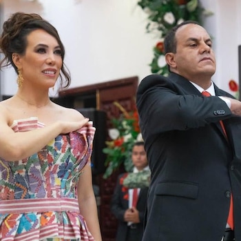 Natalia Rezende Moreira con vestido bordado y Cuauhtémoc Blanco con traje negro colocan su mano derecha en el pecho