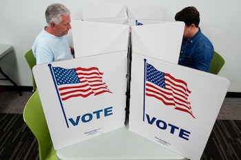 Dos personas cubren sus boletas en un centro de votación instalado en la Biblioteca Regional Tysons-Pimmit, en Falls Church, Virginia, el 31 de octubre de 2024. (AP Foto/Stephanie Scarbrough)