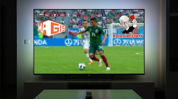 Televisor inteligente mostrando un partido de fútbol borroso. En pantalla se ven claramente los logos de MAGIS TV y ROJADIRECTATV.