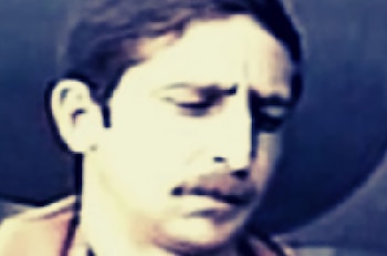 Primer plano pixelado del rostro de un hombre con bigote y cabello oscuro, mirando hacia abajo. La imagen es de baja resolución con tonos fríos