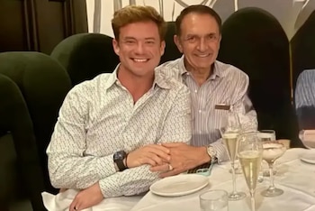 Dos hombres sonríen a la cámara en una mesa de restaurante con mantel blanco, copas y platos. Uno de ellos es el alcalde Dean Trantalis