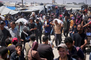 Palestinos cargan bolsas que contienen