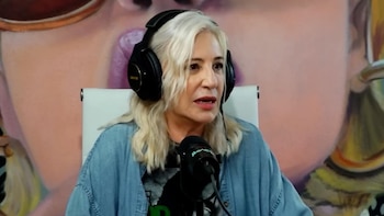 Mercedes Morán, de cabello rubio platinado y con auriculares negros, habla a un micrófono. Viste una camisa de mezclilla sobre una camiseta gris