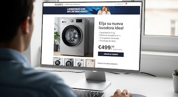Vista trasera de un hombre con camisa azul viendo un monitor de computadora que muestra una página web de Sconro con una lavadora plateada en venta.