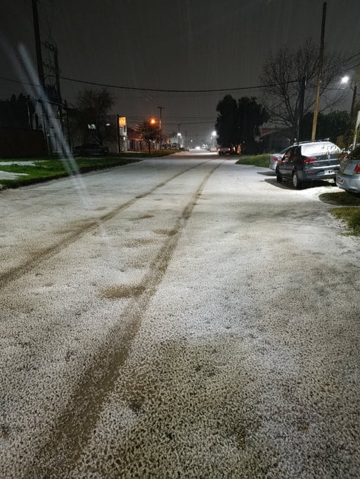 Una calle residencial permanece cubierta por una capa de granizo durante la noche mientras las marcas de neumáticos atraviesan la calzada.