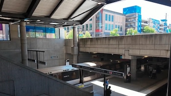 Vista aérea de una estación de tren de MARTA con un tren plateado en la vía, andenes y escaleras de concreto, y edificios de fondo