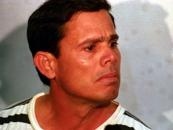 Primer plano de Nestor Moncada Lau, hombre de pelo oscuro, camiseta blanca con rayas negras, mirando a la derecha del encuadre, con expresión facial seria
