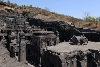 El templo, aunque excavado en la montaña, emerge en parte sobre el nivel del terreno, con fachadas visibles desde el exterior