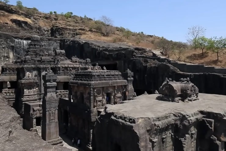 El templo, aunque excavado en la montaña, emerge en parte sobre el nivel del terreno, con fachadas visibles desde el exterior