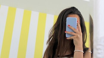 Woman taking selfie with smartphone in front of mirror