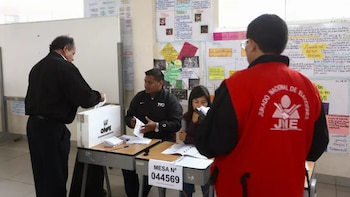 Un elector deposita su voto en una urna frente a miembros de mesa y un supervisor del Jurado Nacional de Elecciones dentro de un aula