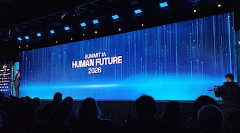 Vista de un escenario con una gran pantalla azul mostrando 'Summit IA Human Future 2026', una oradora en el lado izquierdo y siluetas de la audiencia.