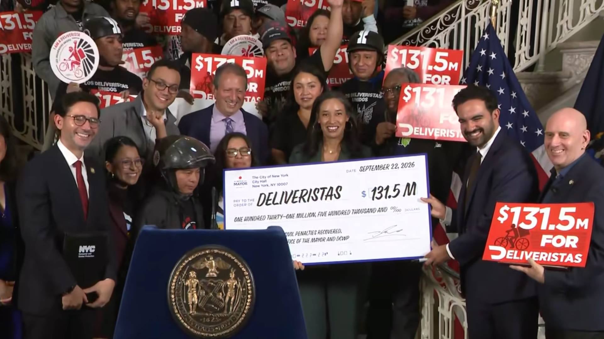 Funcionarios de Nueva York y miembros del grupo Los Deliveristas Unidos sostienen un cheque simbólico por 131,5 millones de dólares durante una ceremonia oficial. (Fox News )