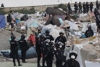 La Policía Nacional desaloja a los migrantes que están asentados en los alrededores de la planta desaladora de la ciudad, en la playa Benítez, por el riesgo que supone para esta instalación. (EFE/Reduan)