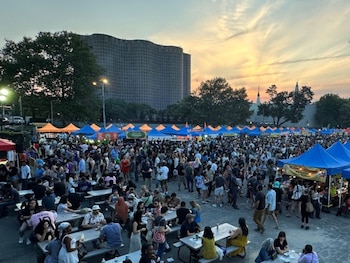 Una multitud recorre decenas de puestos de comida y espacios recreativos durante un concurrido festival urbano en Nueva York, en una jornada marcada por el clima cálido y el ambiente festivo al caer la tarde.