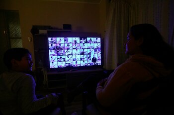 Una madre y su hijo siguen la transmisión a través de un televisor de la octava versión del homenaje de amor colectivo Mil Guitarras para Víctor Jara, en su primera edición on line debido a la pandemia COVID-19. hoy, en Santiago (Chile). EFE/Elvis Gonzalez