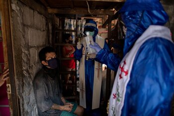 Los sacerdotes Eduardo "Ponpon" Vásquez Jr y Rey Amancio bendicen a un hombre que tiene epilepsia desde la puerta de su casa, Caloocan, Manila, Filipinas, 22 abril 2020.
REUTERS/Eloisa Lopez