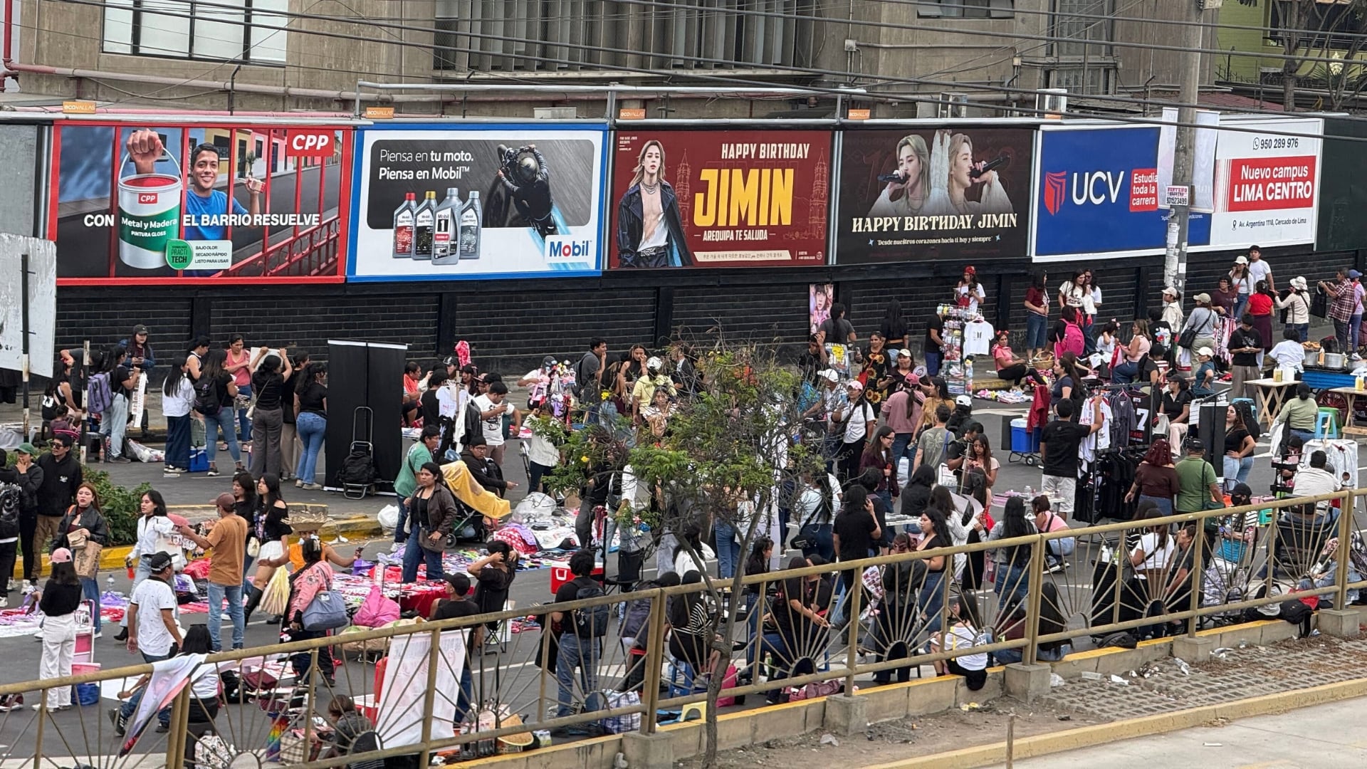 Seguidores del grupo BTS y comerciantes de productos temáticos se congregan en los exteriores del Estadio San Marcos en Lima. (Infobae / Paula Díaz Elizalde)