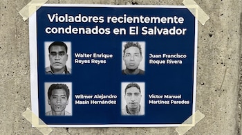 Cartel azul pegado a una pared de concreto con cinta adhesiva que contiene cuatro fotos de rostros masculinos y sus respectivos nombres.