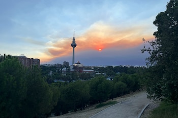 Vista del atardecer desde el pinar del barrio madrileño de La Elipa, influenciado por el humo del incendio que afecta al suroeste de la Comunidad de Madrid. (EFE/Francisco Camino)