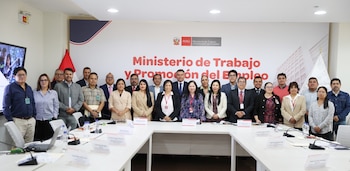 Un grupo de personas posa tras una mesa de reuniones en una sala con un panel del Ministerio de Trabajo y Promoción del Empleo de Perú