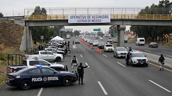 Operativo en autopista con coches de Policía Estatal y Guardia Nacional, agentes dirigiendo el tráfico, conos naranjas y un cartel sobre un puente.