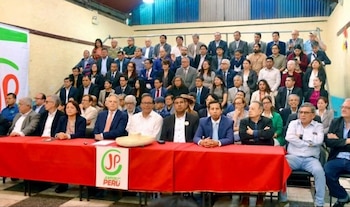 Un gran grupo de personas en un evento político. Varios líderes, incluyendo Anahí Durand y Roberto Sánchez, están sentados en una mesa principal roja