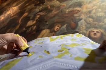 El restaurador Alberto Marcon muestra los signos de decadencia en la obra de arte "Il Paradiso" de 1592 de los artistas venecianos Jacopo Robusti, también conocido como Tintoretto, y su hijo Domenico en el Palacio Ducal de Venecia, el miércoles 7 de diciembre de 2022. (AP Foto/Domenico Stinellis)