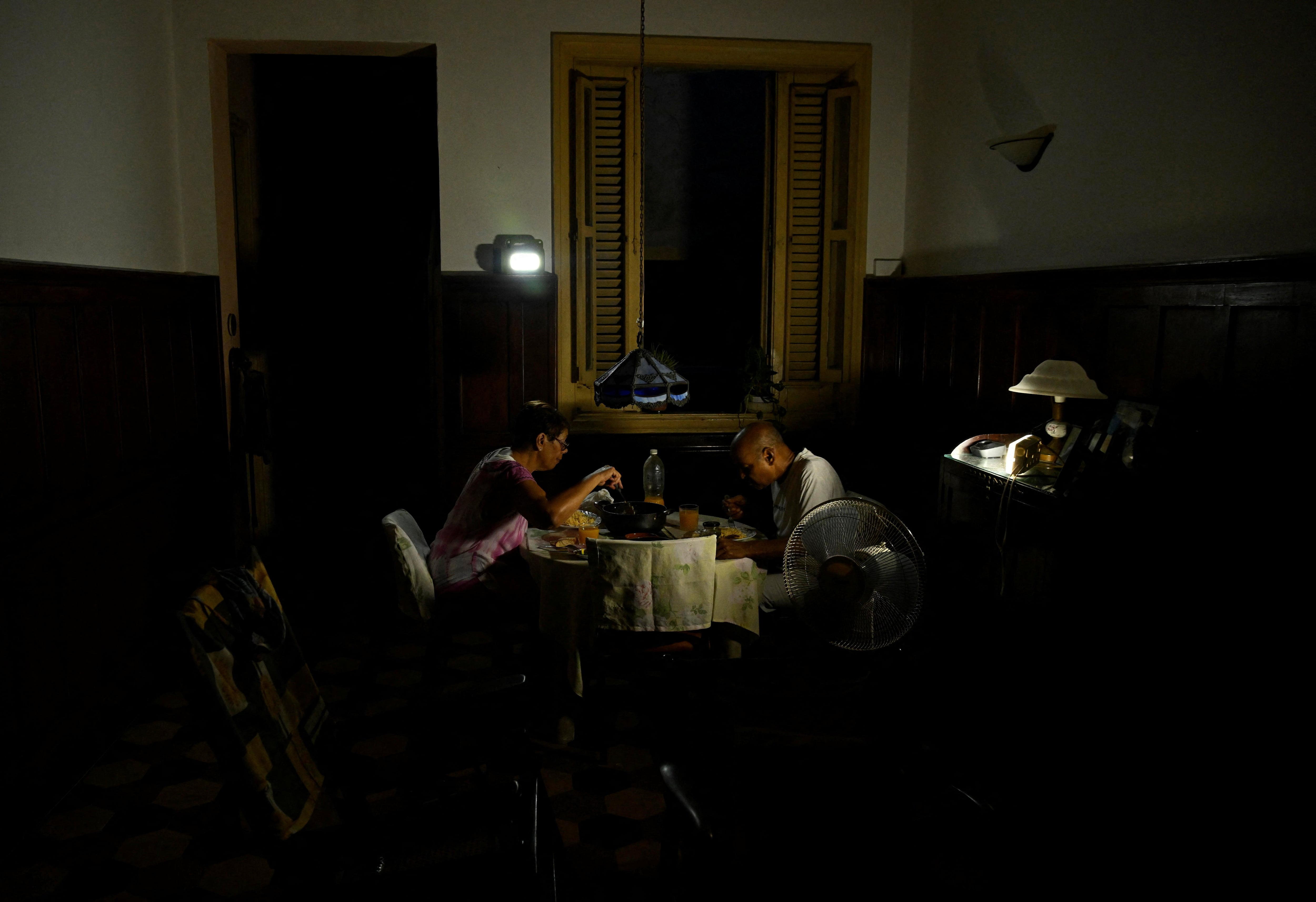Mayra Madariaga, de 72 años, y Renato Lombard, de 74, una pareja de jubilados cuyos tres hijos viven en Estados Unidos, cenan en su casa a la luz de linternas durante un apagón en La Habana, Cuba, el 2 de septiembre de 2025. Cuba ha solicitado apoyo al Programa Mundial de Alimentos de las Naciones Unidas para garantizar el suministro de alimentos a los grupos vulnerables. REUTERS/Norlys Pérez.