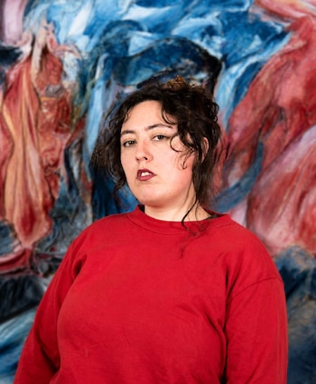 Retrato de Jazmín Kullock con sudadera roja delante de una composición abstracta de texturas en azul, rojo y blanco