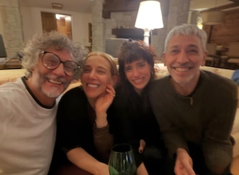 Cuatro personas adultas sonriendo, dos hombres y dos mujeres, en un interior con luz artificial. Se observa un vaso verde