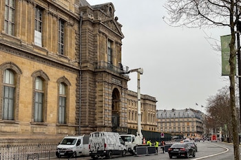 Una plataforma elevadora frente al balcón del Museo del Louvre, furgonetas aparcadas en la vía pública y personas con chalecos reflectantes