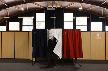 A man leaves a voting booth, in the colours of the French flag, to vote in the first round of the 2022 French presidential election at a polling station in Le Touquet-Paris-Plage, France, April 10, 2022. REUTERS/Christian Hartmann