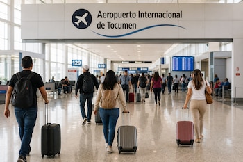 Varias personas caminan de espaldas arrastrando maletas bajo un letrero del Aeropuerto Internacional de Tocumen.