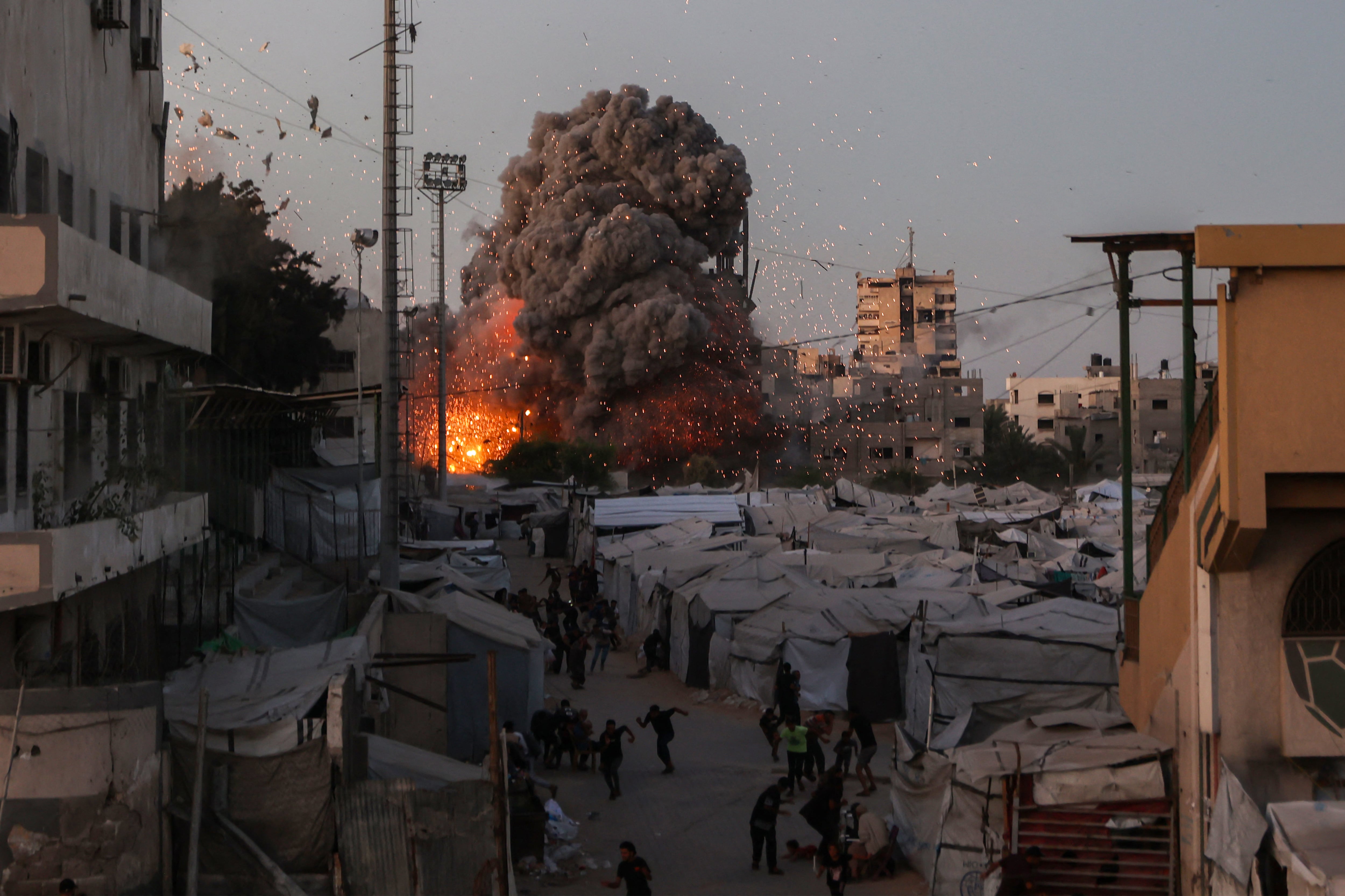 Palestinos buscan refugio mientras el humo y el fuego se elevan durante un ataque israelí contra la mezquita Al-Muttaqin en la ciudad de Gaza el 28 de julio de 2026
(Foto de Omar AL-QATTAA / AFP)