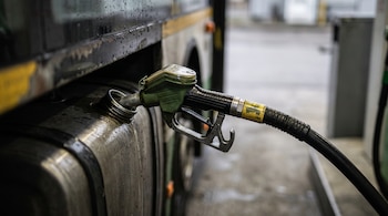 Una boquilla de manguera de combustible insertada en el tanque metálico de un autobús urbano.