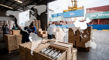Personas en un almacén empacan botellas de pisco en cajas de madera, mientras una grúa carga contenedores en un barco con un mapa mundial superpuesto.