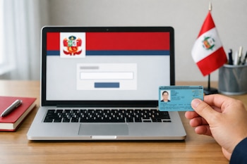 Una mano sostiene un DNI peruano frente a una laptop abierta sobre un escritorio. En la pantalla desenfocada se ve el logo del JNE y un formulario. A la derecha, una bandera de Perú.