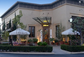 Fachada de un restaurante Il Fornaio con sombrillas blancas en la terraza exterior, mesas, plantas en macetas y un cartel luminoso sobre la entrada