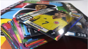 Primer plano de un cromo brillante del futbolista Luis Díaz, vistiendo la camiseta amarilla de Colombia con el número 7, apilado sobre otros cromos.