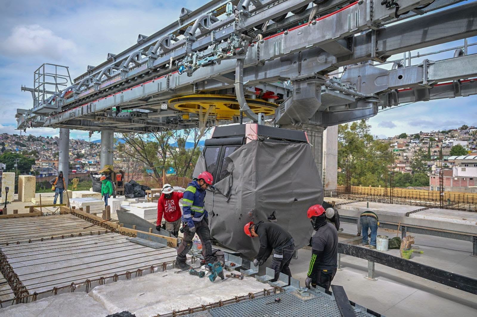 Varios trabajadores instalan componentes en una estación de la Línea 3 del Mexicable tras la conclusión de las obras de cimentación. (FB/ Edoméx Informa)