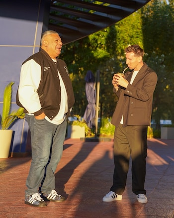 Claudio "Chiqui" Tapia, con chaqueta, y Lionel Messi, con blazer, bebiendo mate, conversan en un exterior soleado