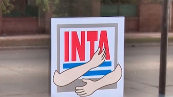Fachada de la Agencia de Extensión Rural del INTA en Brinkmann. Se ve una estatua de vaca Holstein, una bandera y la entrada con puertas de vidrio y logos INTA