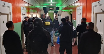 Agentes de policía parados en el pasillo de un pabellón con celdas numeradas a los lados