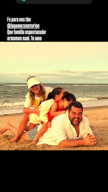 Darío Barassi, una mujer y dos niñas posan sonriendo y riendo en la arena de una playa. Barassi está recostado, las niñas y la mujer encima de él, con el mar de fondo