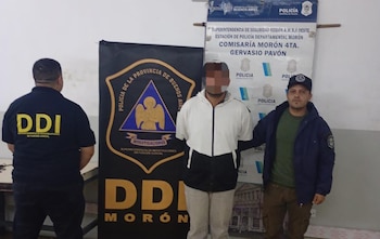 Tres hombres en una habitación: uno de espaldas con una camiseta "DDI", uno con rostro pixelado entre dos oficiales, y carteles policiales de fondo