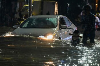Gente circulando en un auto mientras un motociclista empuja su vehículo por una calle inundada provocada por lluvias intensas en Lahore, Pakistán, el lunes 8 de septiembre de 2025. (AP Foto/K.M. Chaudary)