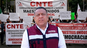 Hombre de mediana edad con chaleco granate y blanco de Morena, hablando frente a pancartas blancas que dicen CNTE y Coordinadora Nacional de Trabajadores de la Educación.