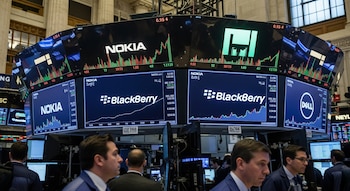 Varias pantallas en la Bolsa de Nueva York muestran los logos de Nokia, BlackBerry y Dell con gráficos de valores, con operadores en el primer plano.